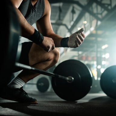 low-angle-view-unrecognizable-muscular-build-man-preparing-lifting-barbell-health-club